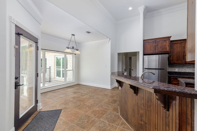 12011 Fm 1150th Rd, Luling, TX 78648 - kitchen with freestanding refrigerator, a breakfast bar area, decorative light fixtures, baseboards, and dark stone countertops