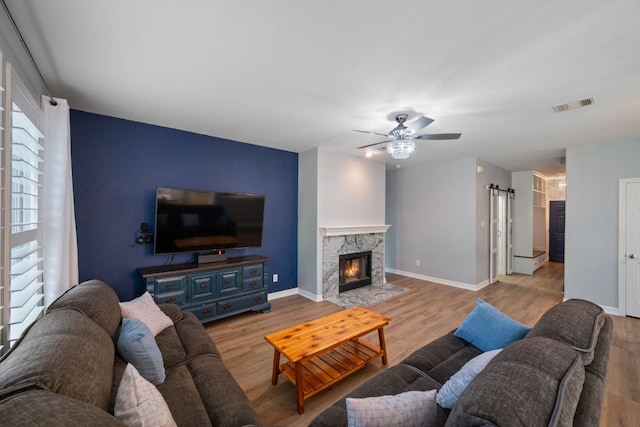 19402 Gale Meadow Dr, Pflugerville, TX 78660 - living room with wood finished floors, a barn door, ceiling fan, baseboards, and a high end fireplace