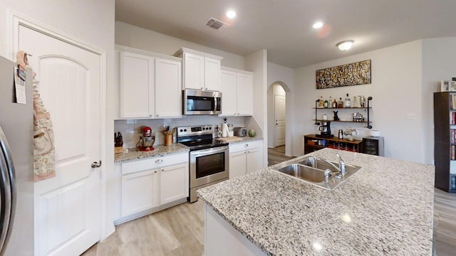 183 Beth Ann Loop, Taylor, TX 76574 - kitchen featuring stainless steel appliances, arched walkways, light wood-style floors, and tasteful backsplash