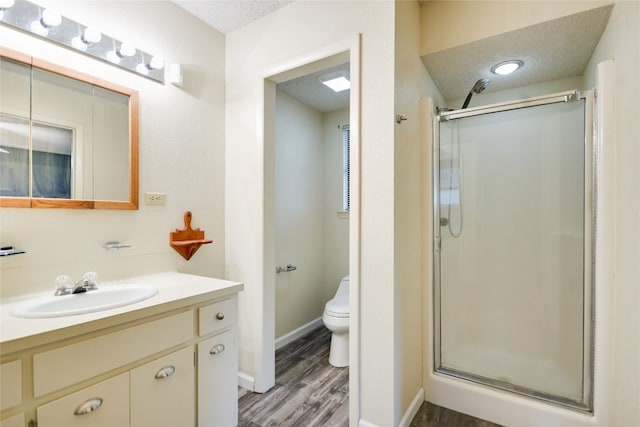 838 Pine Ln, Cottonwood Shores, TX 78657 - full bathroom with a stall shower, wood finished floors, vanity, toilet, and a textured ceiling