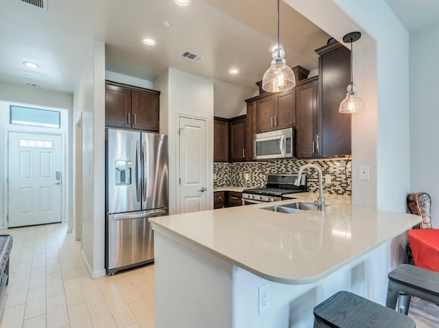 124 Cumberland Rd Unit 401, Austin, TX 78704 - kitchen featuring stainless steel appliances, dark brown cabinetry, a peninsula, backsplash, and light countertops