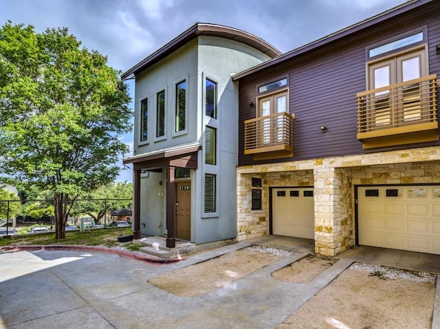 124 Cumberland Rd Unit 401, Austin, TX 78704 - view of front of home with a balcony, stone siding, an attached garage, concrete driveway, and stucco siding