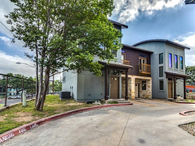 124 Cumberland Rd Unit 401, Austin, TX 78704 - view of front of house featuring central AC unit, stone siding, and a balcony