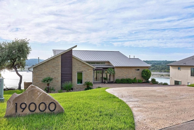 19000 Silver Maple Dr, Lago Vista, TX 78645 - view of front of property with stone siding, a front lawn, metal roof, concrete driveway, and a standing seam roof