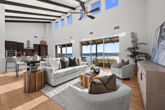 19000 Silver Maple Dr, Lago Vista, TX 78645 - living room featuring ceiling fan, a towering ceiling, plenty of natural light, light wood-style floors, and beamed ceiling