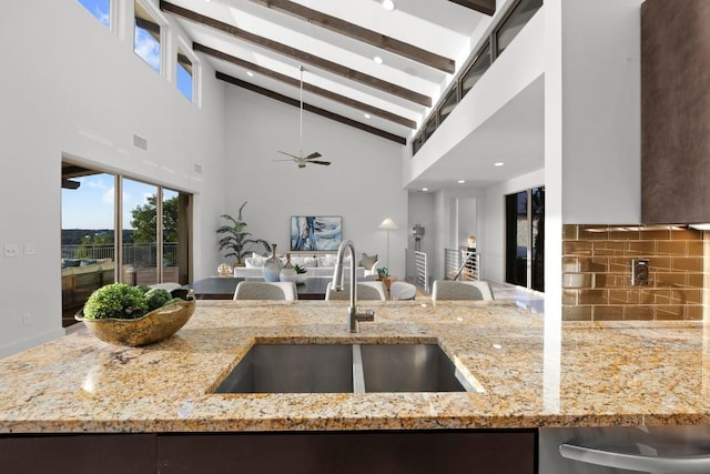 19000 Silver Maple Dr, Lago Vista, TX 78645 - kitchen featuring a sink, open floor plan, backsplash, beamed ceiling, and light stone countertops