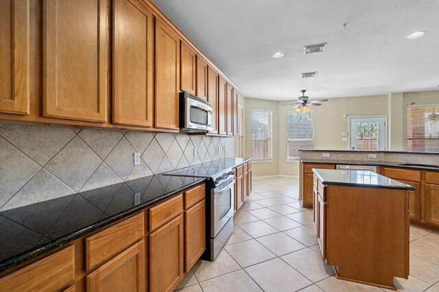 13617 Sun Dapple Ct, Manor, TX 78653 - kitchen with stainless steel appliances, tasteful backsplash, a center island, brown cabinets, and recessed lighting