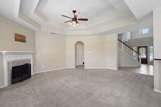 13617 Sun Dapple Ct, Manor, TX 78653 - unfurnished living room featuring a ceiling fan, a raised ceiling, a fireplace, carpet floors, and arched walkways
