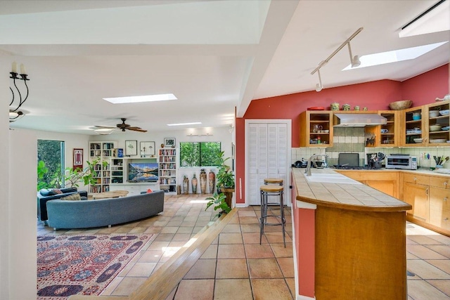 3403 Spanish Oak Dr, Austin, TX 78731 - kitchen with a skylight, tile countertops, range hood, backsplash, and track lighting