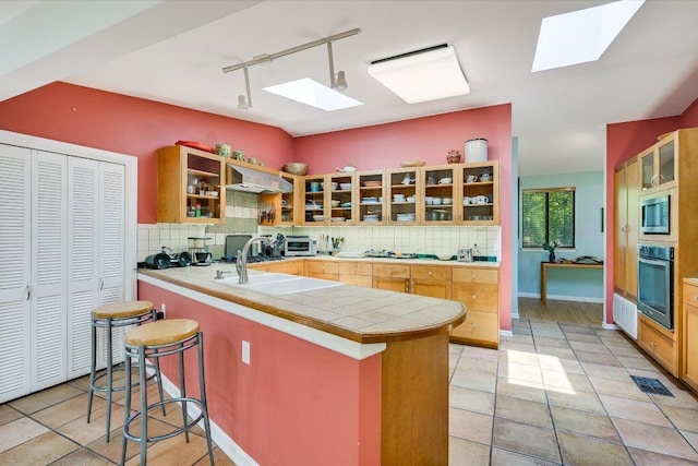 3403 Spanish Oak Dr, Austin, TX 78731 - kitchen featuring a skylight, oven, rail lighting, stainless steel microwave, and backsplash