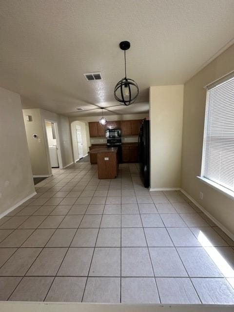 221 Roadrunner Ave, New Braunfels, TX 78130 - kitchen with black appliances, light tile patterned floors, a center island, dark countertops, and baseboards