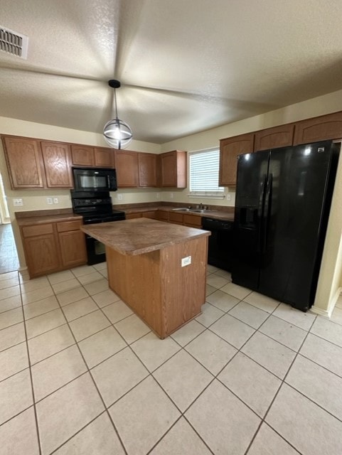 221 Roadrunner Ave, New Braunfels, TX 78130 - kitchen featuring black appliances, a kitchen island, light tile patterned flooring, hanging light fixtures, and a sink