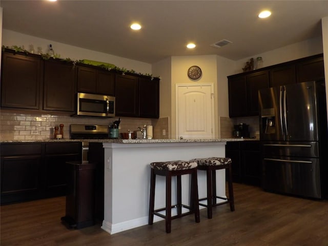 3097 Blantyre Bnd, Round Rock, TX 78664 - kitchen with stainless steel appliances, dark wood-type flooring, tasteful backsplash, a kitchen breakfast bar, and recessed lighting