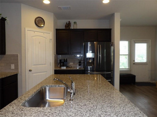 3097 Blantyre Bnd, Round Rock, TX 78664 - kitchen with fridge with ice dispenser, wood finished floors, decorative backsplash, light stone countertops, and a sink