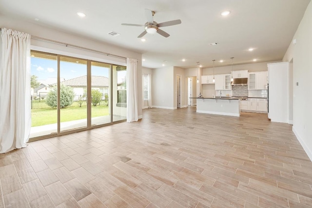 2613 Ibaza Bnd Unit 58, Leander, TX 78641 - unfurnished living room featuring baseboards, a ceiling fan, recessed lighting, a sink, and light wood-type flooring