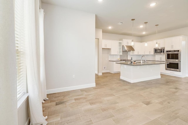 2613 Ibaza Bnd Unit 58, Leander, TX 78641 - kitchen with appliances with stainless steel finishes, under cabinet range hood, dark countertops, white cabinets, and recessed lighting