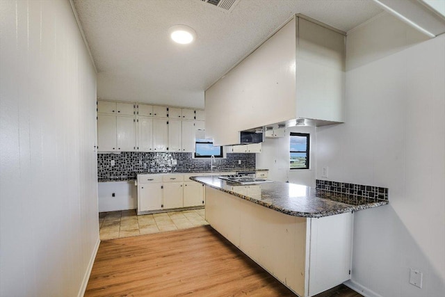 14615 Armstrong Rd, Salado, TX 76571 - kitchen with tasteful backsplash, a peninsula, white cabinets, light wood finished floors, and a sink