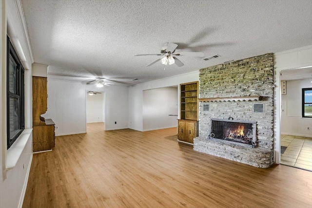 14615 Armstrong Rd, Salado, TX 76571 - unfurnished living room with a fireplace, ceiling fan, light wood-style floors, a textured ceiling, and ornamental molding