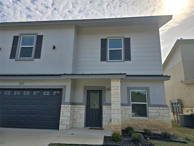 2105 Tiger Trl Unit 503, Round Rock, TX 78665 - view of property featuring central air condition unit, stone siding, a garage, and driveway