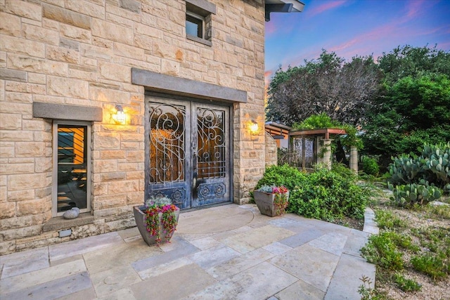 8207 Moon Rise Trl, Jonestown, TX 78645 - exterior entry at dusk featuring french doors and stone siding