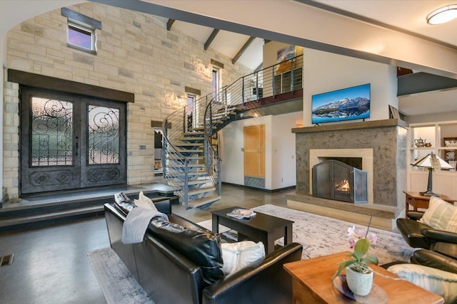 8207 Moon Rise Trl, Jonestown, TX 78645 - living area with a high ceiling, a premium fireplace, french doors, stairway, and beam ceiling