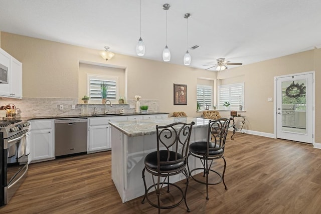 606 Explorer, Lakeway, TX 78734 - kitchen with appliances with stainless steel finishes, a sink, a kitchen breakfast bar, a kitchen island, and white cabinetry