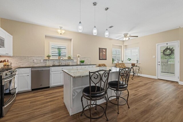 606 Explorer, Lakeway, TX 78734 - kitchen with appliances with stainless steel finishes, a kitchen bar, a kitchen island, white cabinetry, and plenty of natural light