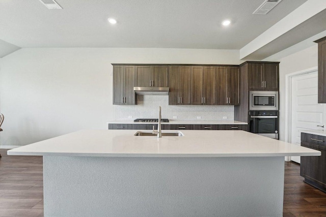 357 Cathedral Mountain Dr, Dripping Springs, TX 78620 - kitchen with appliances with stainless steel finishes, under cabinet range hood, backsplash, an island with sink, and dark brown cabinets