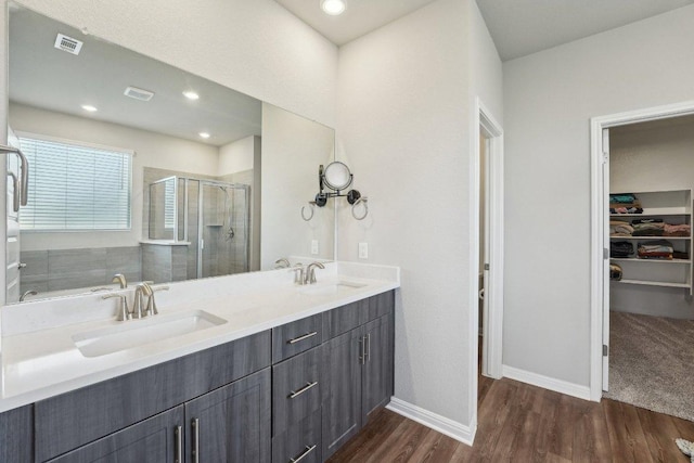 357 Cathedral Mountain Dr, Dripping Springs, TX 78620 - bathroom featuring a walk in closet, a shower stall, wood finished floors, baseboards, and double vanity