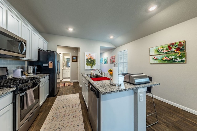 221 Tributary Way, Bastrop, TX 78602 - kitchen with stainless steel appliances, dark wood finished floors, tasteful backsplash, a breakfast bar area, and recessed lighting