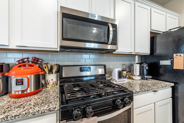 221 Tributary Way, Bastrop, TX 78602 - kitchen featuring appliances with stainless steel finishes, tasteful backsplash, white cabinets, and light stone countertops