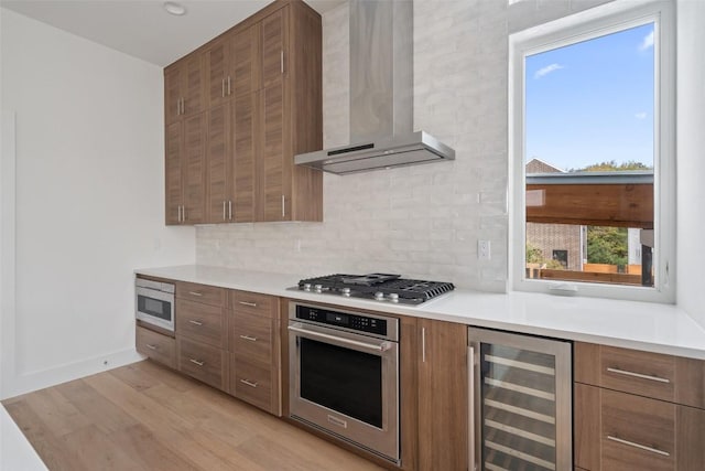 900 S 2nd St Unit 21, Austin, TX 78704 - kitchen with appliances with stainless steel finishes, wall chimney range hood, beverage cooler, light wood-style floors, and tasteful backsplash