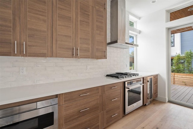 900 S 2nd St Unit 21, Austin, TX 78704 - kitchen featuring stainless steel appliances, beverage cooler, light countertops, brown cabinetry, and light wood-style floors