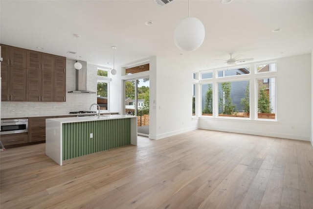900 S 2nd St Unit 21, Austin, TX 78704 - kitchen with ceiling fan, wall chimney exhaust hood, oven, tasteful backsplash, and baseboards