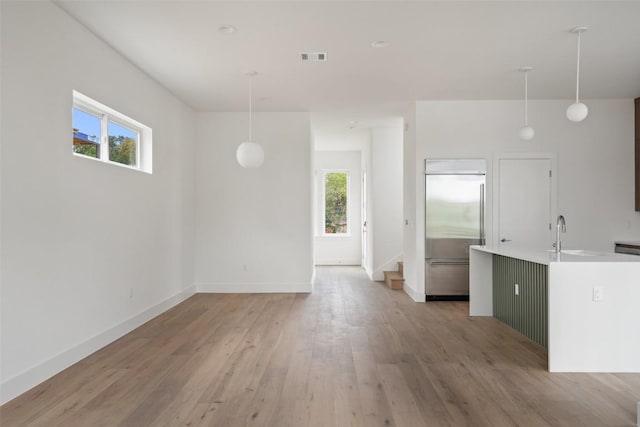 900 S 2nd St Unit 21, Austin, TX 78704 - unfurnished living room featuring plenty of natural light, light wood-style floors, baseboards, and a sink
