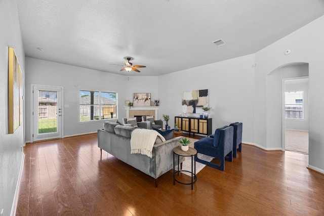 805 Meadow Bluff Ct, Round Rock, TX 78665 - living room featuring arched walkways, ceiling fan, wood finished floors, a tile fireplace, and baseboards