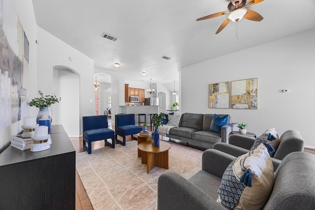 805 Meadow Bluff Ct, Round Rock, TX 78665 - living room with arched walkways, ceiling fan, light wood-style floors, and a chandelier