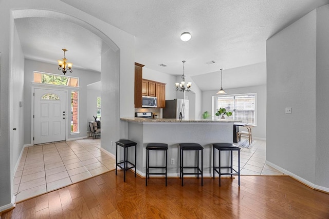 805 Meadow Bluff Ct, Round Rock, TX 78665 - kitchen featuring a chandelier, appliances with stainless steel finishes, brown cabinetry, and a breakfast bar