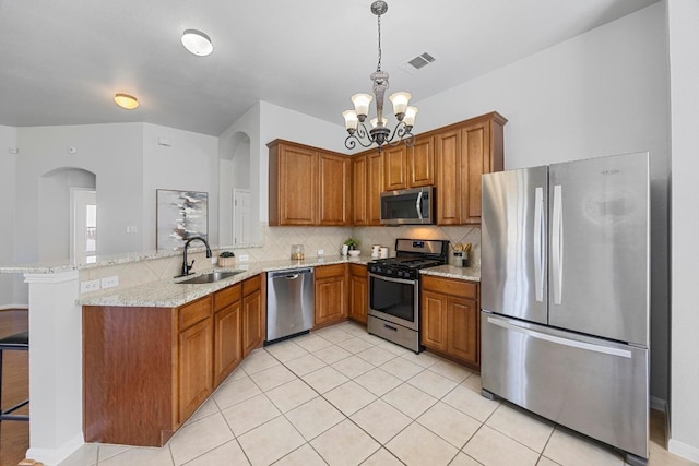 805 Meadow Bluff Ct, Round Rock, TX 78665 - kitchen with appliances with stainless steel finishes, a sink, a peninsula, brown cabinetry, and a chandelier