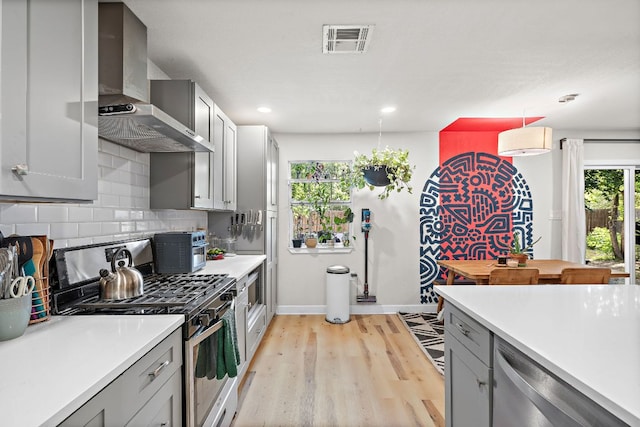 4708 Turnstone Dr, Austin, TX 78744 - kitchen featuring wall chimney exhaust hood, appliances with stainless steel finishes, baseboards, light countertops, and decorative backsplash