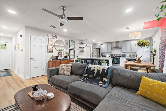 4708 Turnstone Dr, Austin, TX 78744 - living room with light wood-style floors, a ceiling fan, recessed lighting, a baseboard radiator, and baseboards