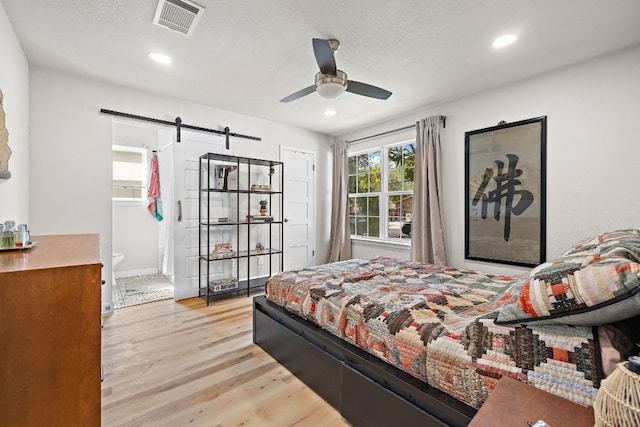 4708 Turnstone Dr, Austin, TX 78744 - bedroom featuring a barn door, light wood finished floors, recessed lighting, ensuite bath, and baseboards