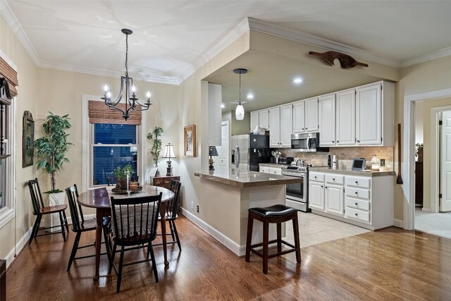 40 Tournament Way Unit G-32, The Hills, TX 78738 - kitchen featuring appliances with stainless steel finishes, light wood-style floors, a chandelier, tasteful backsplash, and crown molding