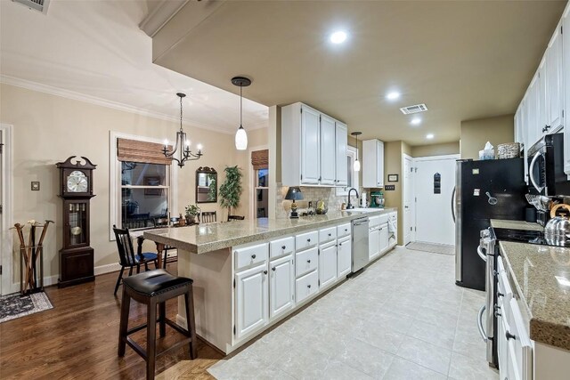 40 Tournament Way Unit G-32, The Hills, TX 78738 - kitchen with appliances with stainless steel finishes, a peninsula, white cabinetry, backsplash, and a breakfast bar area