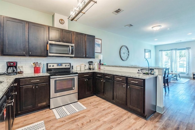 12160 Abbey Glen Ln, Austin, TX 78753 - kitchen featuring stainless steel appliances, a peninsula, light wood-style floors, light stone counters, and recessed lighting