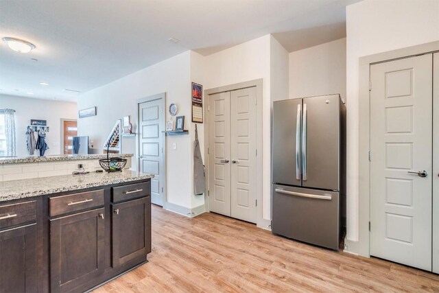 12160 Abbey Glen Ln, Austin, TX 78753 - kitchen with freestanding refrigerator, dark brown cabinets, light wood finished floors, and light stone counters