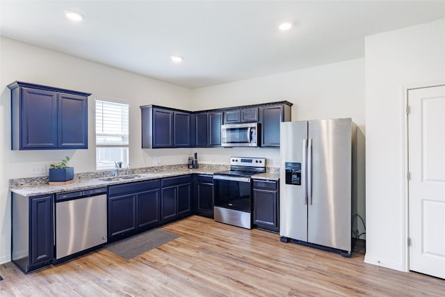 301 Wonderful Life Way, Jarrell, TX 76537 - kitchen with stainless steel appliances, light wood-type flooring, a sink, light stone countertops, and recessed lighting