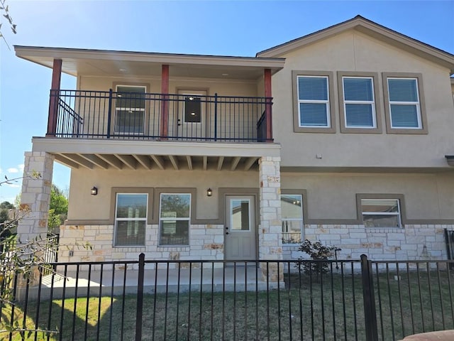 2105 Tiger Trl Unit 603, Round Rock, TX 78665 - view of front of house with a balcony, stone siding, a fenced front yard, and stucco siding