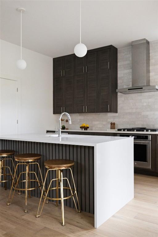 900 S 2nd St Unit 20, Austin, TX 78704 - kitchen with wall chimney exhaust hood, stainless steel oven, light countertops, and light wood finished floors