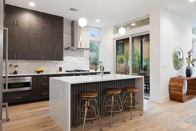 900 S 2nd St Unit 20, Austin, TX 78704 - kitchen featuring wall chimney exhaust hood, a kitchen breakfast bar, backsplash, light countertops, and recessed lighting